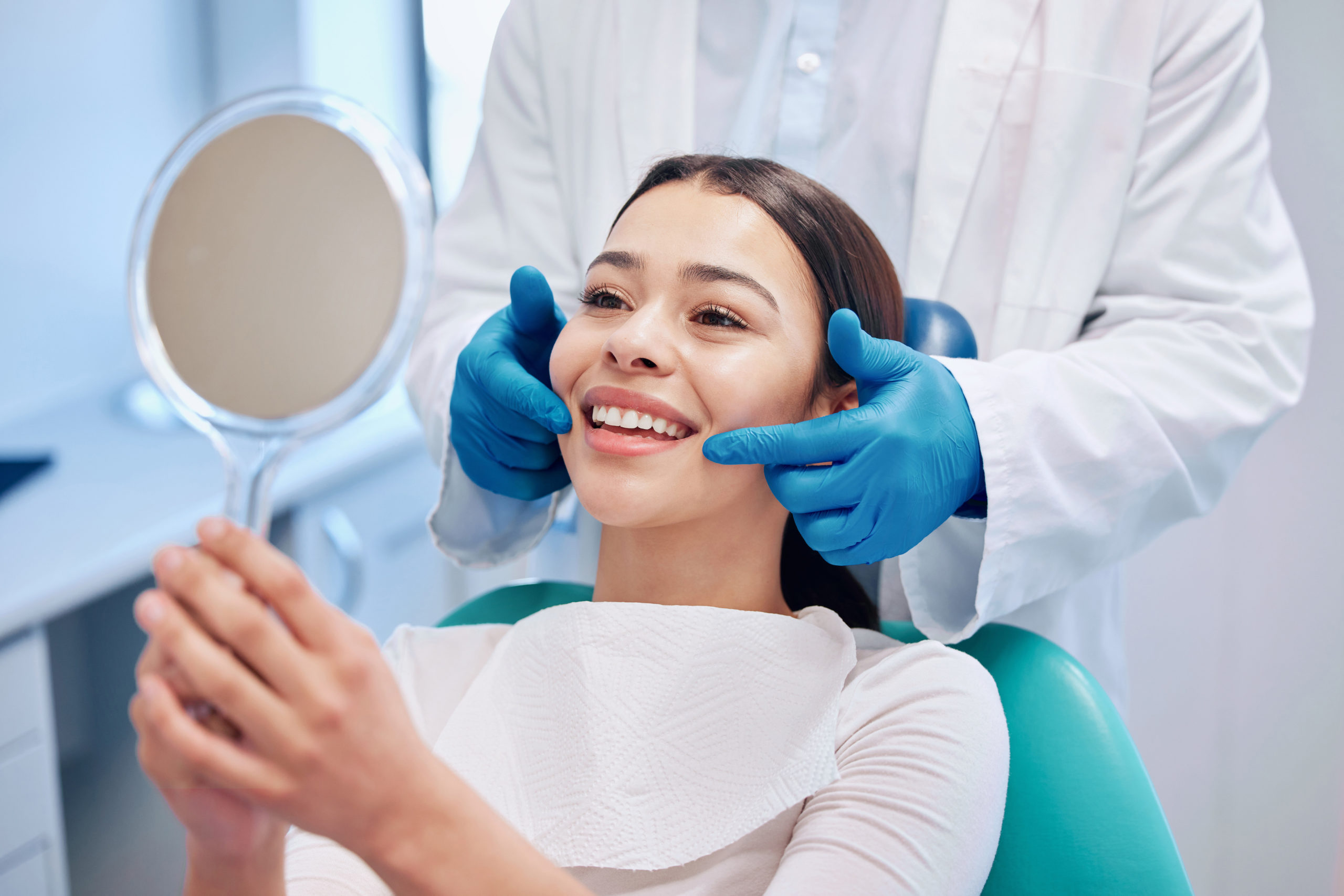 歯科医院で鏡で自分の歯並びを確認する女性