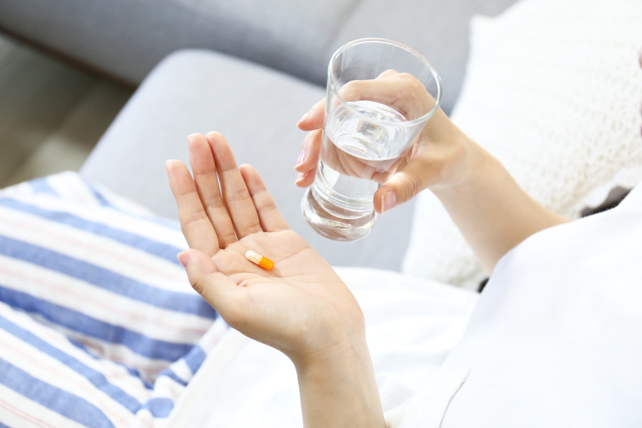 虫歯治療後の痛みの応急処置として痛み止めを飲む男性