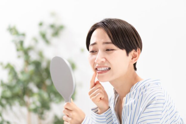 インプラント周囲炎が気になって鏡で確認する女性