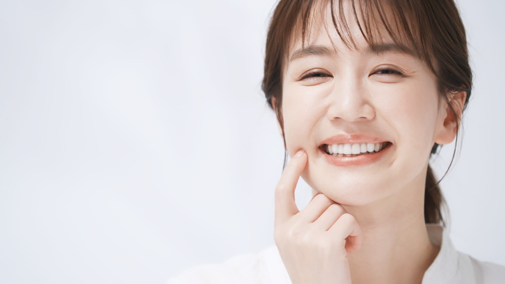 きれいな歯を指さし微笑む女性