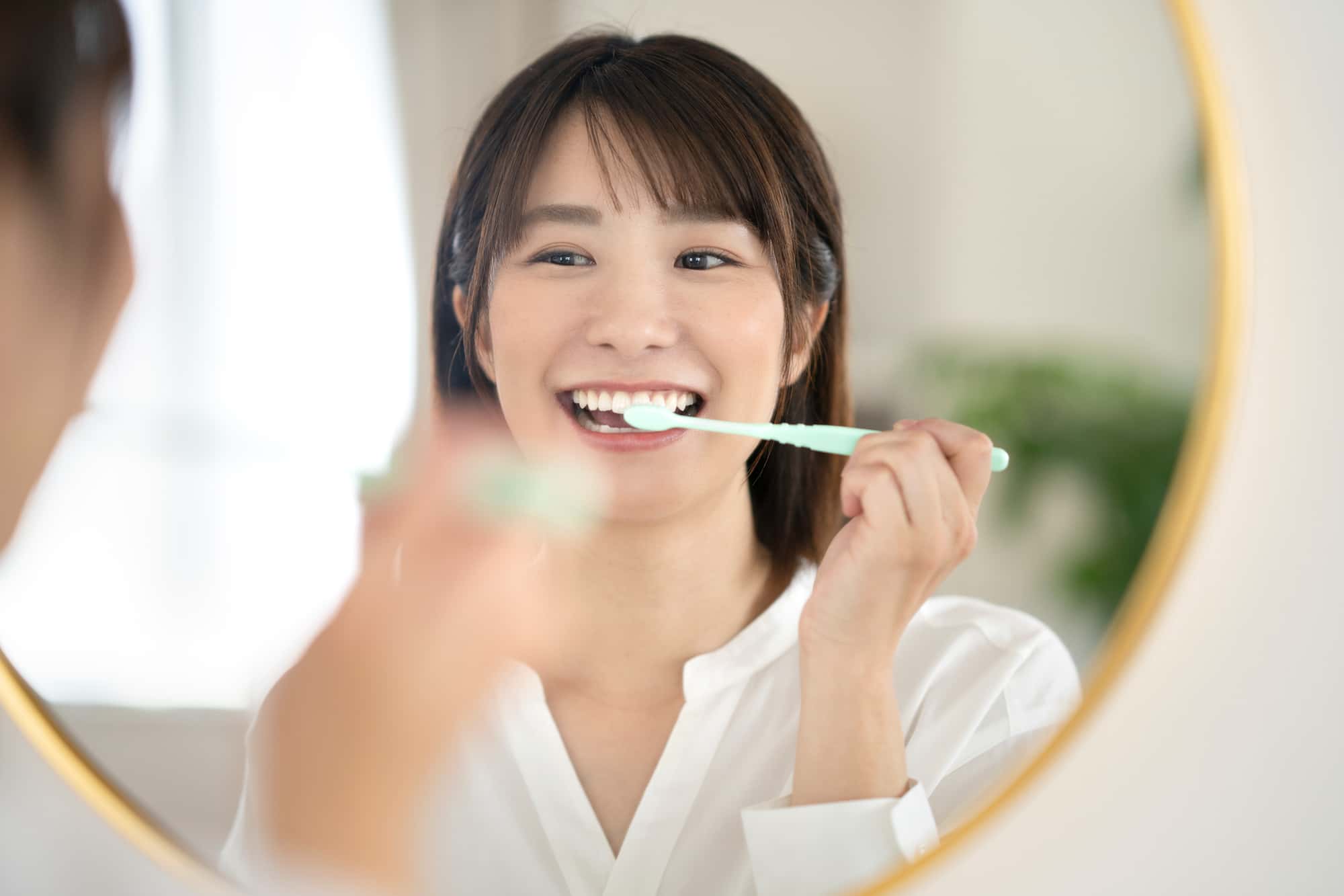 オフィスホワイトニングの効果を維持するために丁寧に歯みがきをする女性