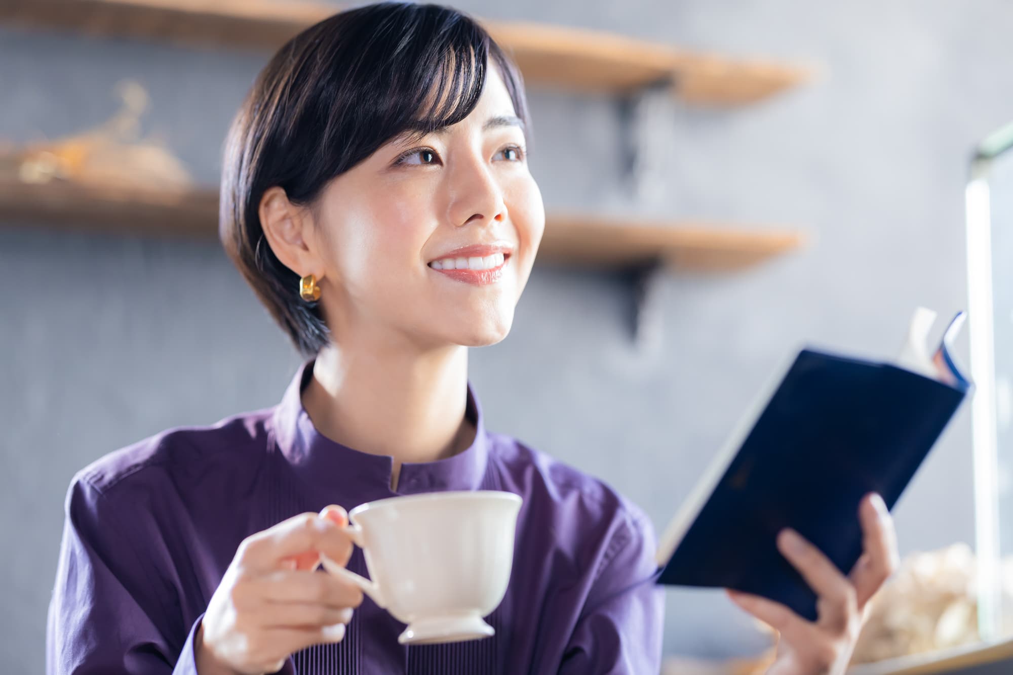 奥歯の虫歯を治療して笑顔でコーヒーを飲みながら読書をしている女性