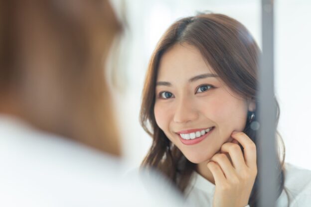 デュアルホワイトニングで白くなった歯を鏡で確認する女性
