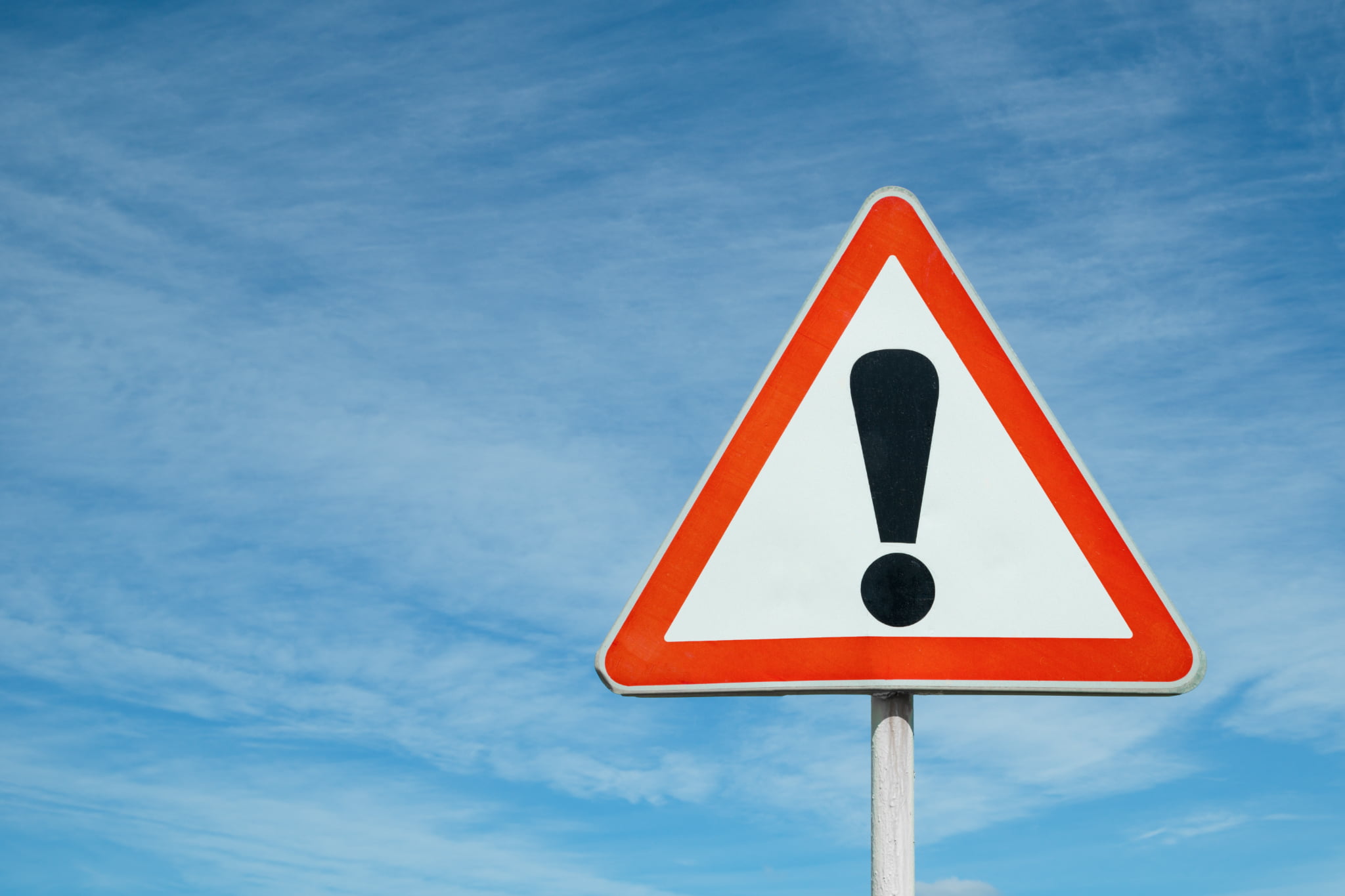 高齢者がインプラント治療を受ける場合の注意点を表現した青空の下のビックリマーク標識